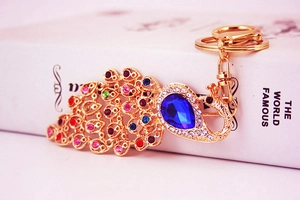 Close-up of colorful peacock keychain with blue pear-shaped stone and vibrant rhinestones