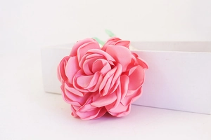Gros plan d'un porte-clés rose en soie à côté d'un coffret cadeau blanc élégant