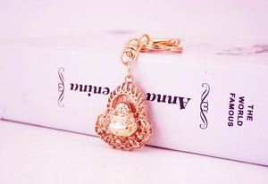 Close-up of golden Maitreya Buddha keychain with hollow flame patterns on book edge