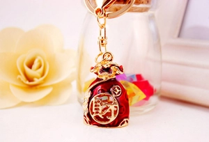 Detailed close-up of a golden Chinese money bag keychain with red enamel and crystals