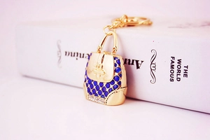 Macro shot of gold handbag keychain with blue enamel texture and white rhinestones