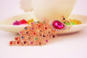 Detail of colorful peacock brooch with pink crystal and multicolored rhinestones