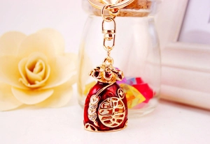 Detail of red enamel fortune bag keychain with gold Fu character and crystal inlay