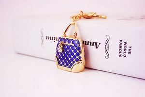 Detail of golden handbag keychain with navy blue diamond texture and sparkling rhinestone