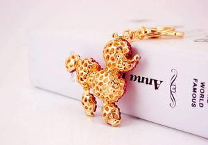 Close-up of golden poodle keychain featuring intricate hollow design and pink rhinestones
