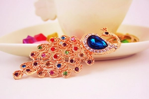 Detailed close-up of a golden peacock keychain with vibrant multicolored rhinestones
