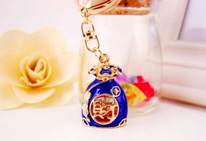 Detail of blue enamel lucky money bag keychain with golden character for wealth
