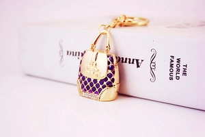 Detail view of gold handbag keychain with purple grid pattern and sparkling rhinestones