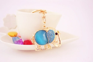 Detailed view of golden elephant keychain with blue gemstone hanging on a white cup