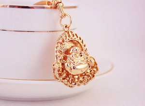 Macro shot of a golden Laughing Buddha keychain pendant on a white coffee cup
