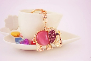 Detail of metal elephant keychain with pink cat eye stone and purple rhinestones