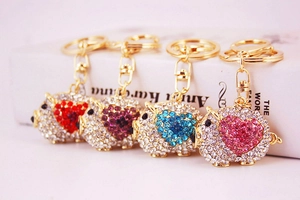 Detail view of four cute pig keychains with sparkling rhinestones in assorted colors