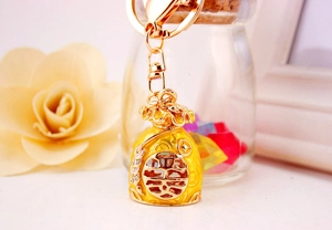 Detailed close-up of a gold-plated Chinese lucky bag keychain with enamel and koi fish
