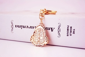 Detailed close-up of golden Buddha head keychain with intricate relief patterns
