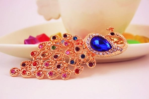 Close-up of colorful crystal peacock keychain with blue teardrop stone and gold plating