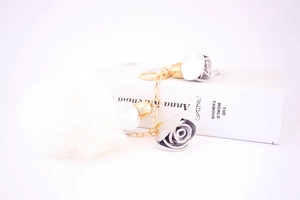 Detail of silver fabric roses and white fluffy faux fur pompom with golden metal chain