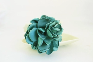 Gros plan d'un élégant charme de rose en satin bleu sarcelle sur un plateau en porcelaine