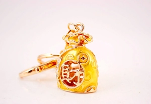 Detail of golden money bag keychain with yellow enamel and Chinese Cai character