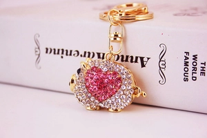 Close-up of golden pig keychain featuring sparkling pink heart rhinestones and D-ring