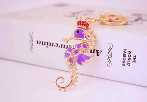 Détail d'un porte-clés hippocampe doré avec émail violet et couronne en cristaux brillants