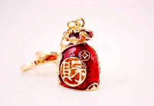 Macro shot of gold-plated lucky money bag keychain with red enamel and crystals