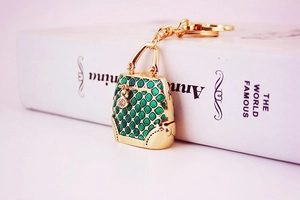Detail of green enamel handbag keychain with gold metal frame and a single rhinestone