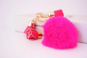 Detail of rose pink fluffy faux fur pompom keychain with golden rose bud charms