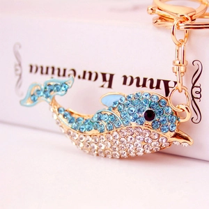 Sparkling rhinestone dolphin keychain in blue and gold on a white book backdrop