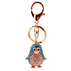 Sparkly crystal cartoon penguin keychain with gold plating and blue rhinestones on white background
