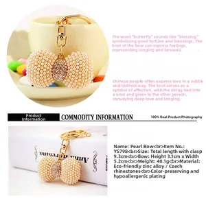 Detail view of pearl bow keychain with crystals and gold-plated alloy ring for bags