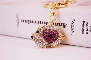 Close-up of heart-patterned sparkling rhinestone pig keychain with golden metal clasp