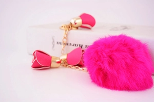 Close-up of bright pink faux fur pompom keychain with golden chains and rose charms