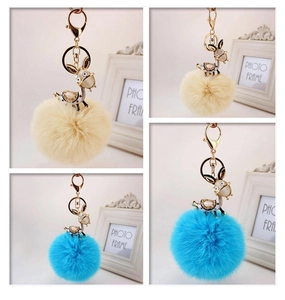 Detailed view of cute rhinestone donkey keychains with plush faux fur balls in beige and blue
