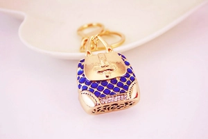 Detailed close-up of a blue enamel handbag keychain with gold trim and white rhinestones