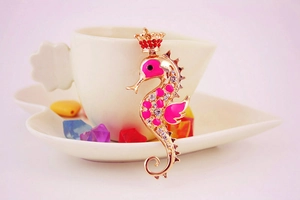 Vue détaillée du pendentif hippocampe avec couronne rouge et émail rose sur porcelaine
