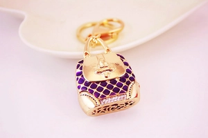 Close-up of purple enamel handbag keychain with sparkling rhinestones on gold metal