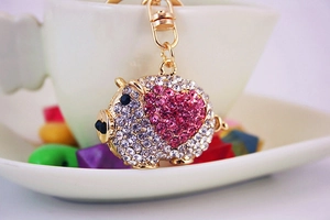 Detailed view of pig keychain with sparkling crystals and heart on a white cup