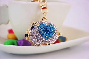 Macro view of crystal encrusted pig keychain with blue rhinestone heart detail