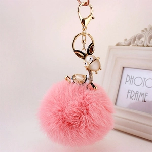 Macro detail of a pink faux fur pompom keychain with a rhinestone donkey pendant