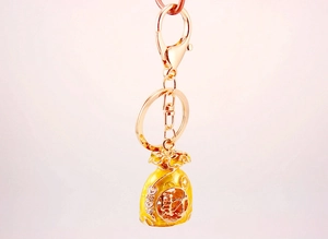 Detailed close-up of a golden Chinese lucky bag keychain with enamel Cai character charm
