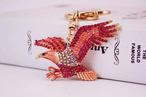 Détail d'un porte-clés aigle doré serti de strass brillants rouges et roses