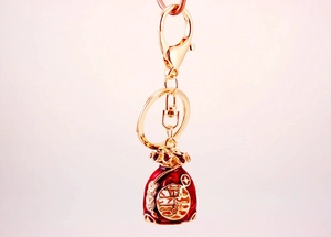 Detailed close-up of a red enamel money bag keychain with gold plating and crystals