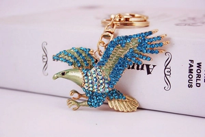 Détail d'un porte-clés aigle avec strass bleus sur un support en alliage doré