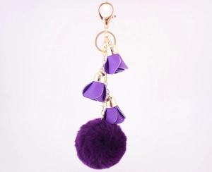 Detail view of purple leather flowers and soft fur ball keychain with golden metal clasp