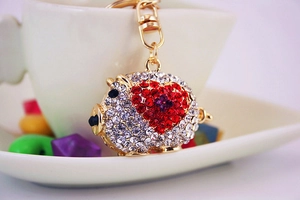 Close-up of golden sparkling rhinestone pig keychain with red heart detail on coffee cup