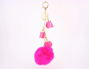 Detail of hot pink faux fur pom pom keychain with leather flower charms and gold chain