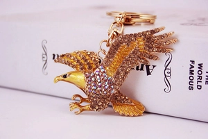 Gros plan d'un porte-clés aigle doré avec strass brillants et plumes détaillées