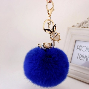 Close-up of deep blue fur ball keychain with rhinestone animal charm and gold lobster clasp