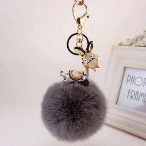Detailed close-up of dark grey faux fur keychain with a gold donkey rhinestone pendant