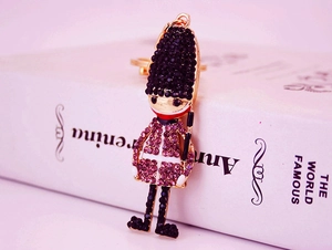 Close-up of royal guard keychain with pink and black crystals against a book